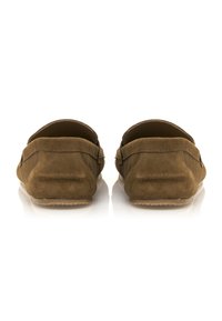 Chaussures à enfiler en daim marron avec des talons arrondis, des détails de couture subtils, et des semelles en caoutchouc lisses visibles au niveau du talon.