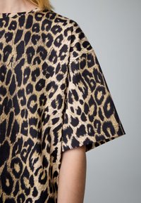 Übergroßes Oberteil mit Leopardenmuster aus schwarzer und beiger Baumwolle; verfügt über kurze Ärmel und eine lockere Passform mit sichtbaren Nahtdetails.