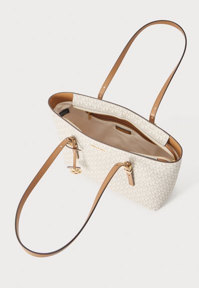 Sac cabas beige avec des anses en cuir marron, motif monogramme, ouverture supérieure dévoilant la doublure intérieure beige et une petite poche zippée à l'intérieur.