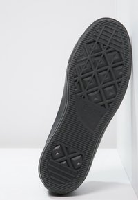 Černá gumová podrážka boty s texturovaným, geometrickým vzorem. Obsahuje vyvýšené trojúhelníkové akcenty a branding "Converse All Star".