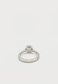 Ασημένιο δαχτυλίδι αρραβώνων με κεντρικό διαμάντι και μικρότερα διαμάντια ενσωματωμένα κατά μήκος της βέρας σε λευκό φόντο.