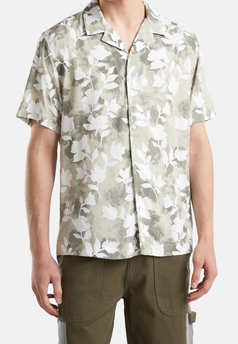 Camicia a maniche corte con bottoni di colore grigio chiaro con motivo floreale bianco. Il tessuto ha una texture liscia e presenta un design del colletto rilassato.