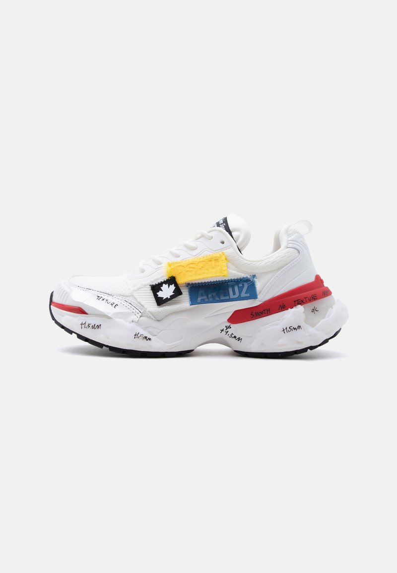 Λευκό αθλητικό παπούτσι με μαύρη σόλα, πολύχρωμες υφασμάτινες επιδιορθώσεις, κόκκινες λεπτομέρειες και χειρόγραφες λεπτομέρειες κειμένου στη σόλα και στις πλευρές.