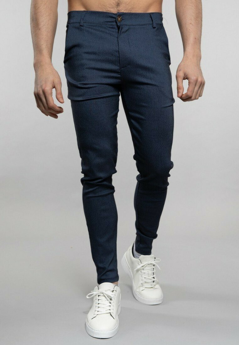 Pantalons bleu marine fuselés avec un motif texturé, dotés d'une fermeture à bouton, de poches avant et d'une coupe slim, associés à des sneakers blanches.