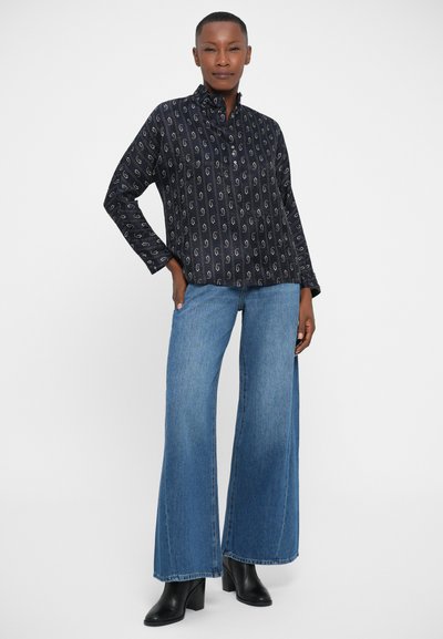 Navy gemusterde overhemd met kraag, gecombineerd met brede blauwe denim jeans en zwarte enkellaarsjes met hak.