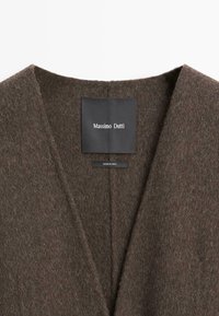 Brun cardigan i uldblanding med dyb V-hals, der har et mærke og en blød, tekstureret finish. Fremstillet i Kina.