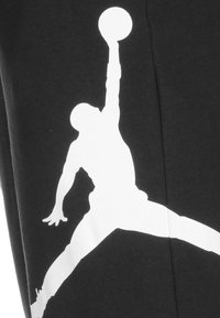 Czarna bluza z dużą białą sylwetką koszykarza skaczącego do wsadu, o gładkiej fakturze i sportowym wzornictwie.