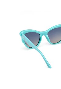 Ochelari de soare turquoise cu un design cat-eye, având lentile gradiente și un cadru din plastic lucios. Brațele sunt elegante și ușor curbate.