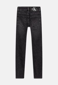 Svarta denimjeans med figurnära siluett, fem fickor och en Calvin Jeans-logotyp på bakre midjebandet. Mjuk textur.