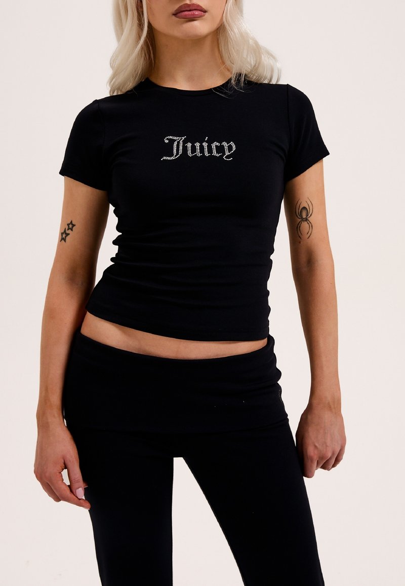 T-shirt nera aderente realizzata in tessuto morbido con maniche corte, che presenta un logo "Juicy" in strass argentati sulla parte anteriore.