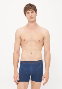 Marineblaue Boxershorts mit einem roten "JACK & JONES" Bund, aus glattem Stoff, mit passgenauer Form und Kontrastnähten.