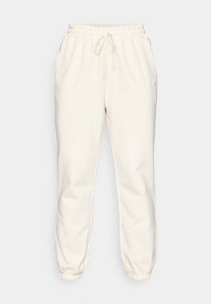 Sudadera de color crema hecha de tejido suave, con cinturilla elástica y cordón, bolsillos laterales y puños ajustados en los tobillos.