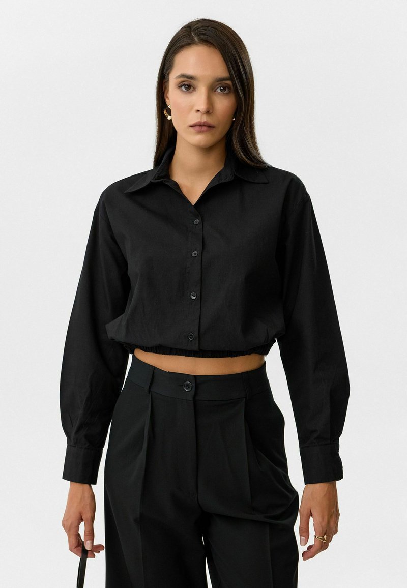 Zwarte, cropped button-up blouse met lange mouwen en een kraag, voorzien van een gather-zoom en een soepele stofstructuur.