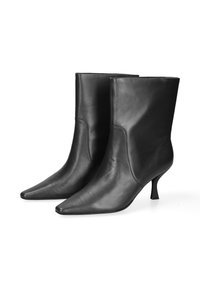 Stivali alla caviglia in pelle nera con punta affusolata e tacco sottile. Texture liscia, design minimalista senza hardware o decorazioni visibili.