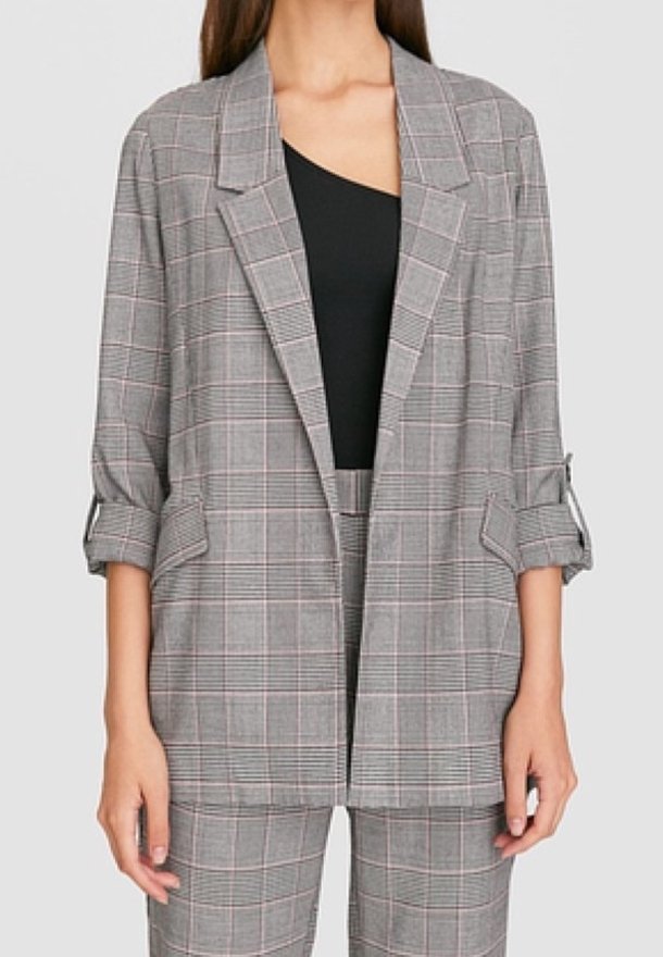 Blazer à carreaux gris avec une coupe décontractée, doté d'un col cranté, de manches retroussées et d'accents rouge clair, associé à un pantalon à carreaux assorti.