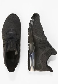 Czarne sportowe sneakersy z teksturowanym siateczkowym wierzchem, z wiązaniami i przezroczystą podeszwą. Posiadają ergonomiczne akcenty dla wsparcia.