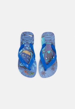 Chanclas azules con suela texturizada, presentan personajes de dibujos animados sobre un fondo azul estampado. Hechas de goma con correas azules.