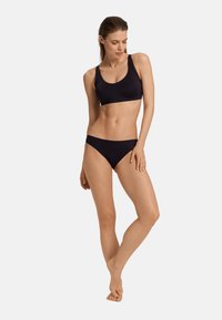 Set bikini nero composto da top bralette e slip a vita bassa. Materiale liscio ed elasticizzato con dettagli minimi e design aderente.
