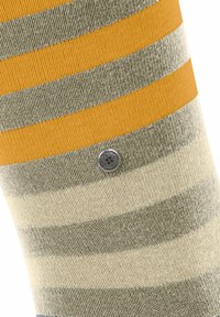 Chaussette rayée tricotée aux couleurs jaune, gris et beige, avec une texture lisse et un accent métallique sur le côté.