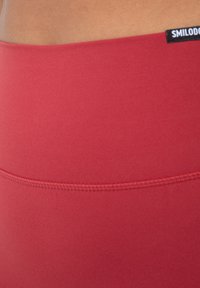 Rode high-waisted leggings gemaakt van een zachte, rekbare stof. Heeft een platte tailleband en subtiele stikdetails. Etiket in de bovenhoek.