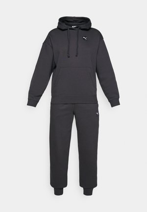 Schwarzer Kapuzenpullover und passende Sweatpants aus weichem Material. Verfügt über eine Kängurutasche und Logo-Elemente auf beiden Teilen.