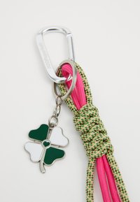 Green and white four-leaf clover charm on a silver keychain. Knotted pink and green paracord with a silver carabiner clasp.