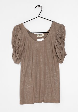 Blouse taupe à manches courtes avec manches bouffantes froncées et un subtil éclat, suspendue sur un cintre noir sur fond blanc.