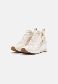 Sneaker bianche senza lacci con accenti beige testurizzati, caratterizzate da un design cucito, una chiusura con zip e una suola in gomma rialzata.