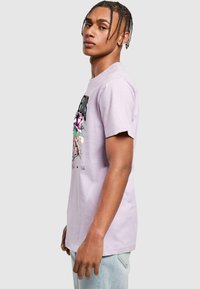 Lilac cotton t-shirt featuring a graphic design with floral accents and text. Short sleeves and a relaxed fit with a round neckline.