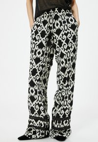 Wijdvallende broek met een zwart-wit dierenprint, voorzien van een koordtaille en zwarte franjes, gemaakt van lichte stof.