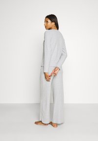 Ljusgrå, ribbat lounge-set som består av en långärmad topp och vida byxor, med en avslappnad passform och mjuk textur.