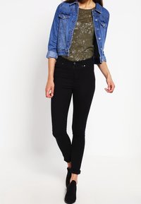 Denimjacka med rullade ärmar, olivgrön blommig t-shirt, svarta skinny jeans och ankelstövlar. Enkel design, enfärgat och figursydd.