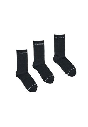 Tres calcetines negros tipo tripulación con texto blanco "GIRLFRIEND" cerca de la parte superior y una línea blanca a lo largo de los dedos, mostrados sobre un fondo blanco.