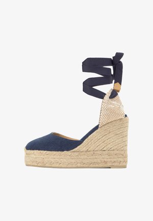 Cuña espadrille azul marino con suela trenzada de yute y cintas para atar al tobillo en tela azul marino.