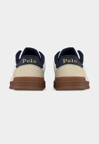 Ζευγάρι λευκά αθλητικά παπούτσια με ναυτικό μπλε και μπεζ λεπτομέρειες, καφέ σόλες και λογότυπο "Polo" στο πίσω μέρος γύρω από τις φτέρνες.