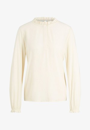 Blusa de manga larga en color crema con cuello y puños fruncidos, cierre frontal con cremallera y textura de tela suave.