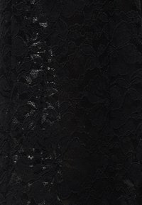 Μαύρο δαντελένιο ύφασμα με floral μοτίβα και διαφανείς περιοχές που δημιουργούν ένα ευαίσθητο, υφασμένο σχέδιο.