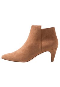 Tan suede nilkkuri, jossa on terävä kärki, minimalistinen muotoilu ja matala korko. Ulkopuolella on leikattu yksityiskohta.