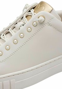 Sneaker bianco in pelle con accenti dorati, sistema di allacciatura con borchie simili a perle e suola in gomma texturizzata.