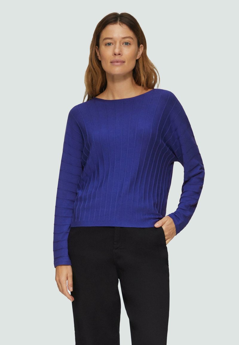 Blauer gerippter Strickpullover mit langen Ärmeln, rundem Halsausschnitt und lässiger Passform. Kombination mit schwarzen Hosen für einen lässigen Look.