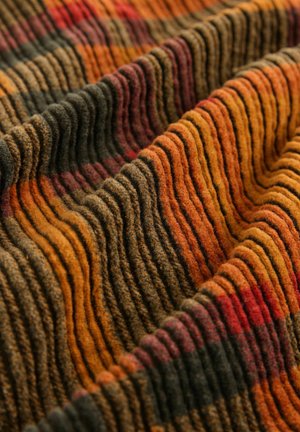 Strukturierter Stoff in warmen Farbtönen von Orange, Braun und Rot, mit wellenförmigen Rippungen und einer weichen, flauschigen Oberfläche, die einen geschichteten Effekt erzeugt.