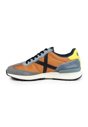 Sneaker caratterizzata da un mix di tessuto arancione e suede grigio, con dettagli neri, una suola intermedia bianca e un dettaglio sul tallone giallo. Inclusi i lacci neri.