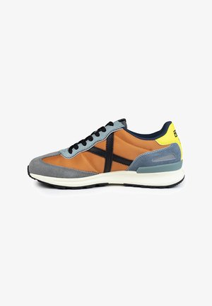 Sneaker featuring a mix of orange fabric and grey suede, with black accents, a white midsole, and a yellow heel detail. Black laces included.