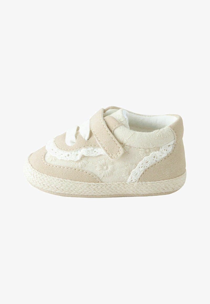 Zapato infantil beige con bordado floral, banda de velcro y acentos de encaje blanco. Textura suave con suela tejida. Diseño de punta redondeada.