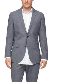 Grijze geblokte colbert met notches, sluiting met één knoop en twee frontzakken. Gecombineerd met een wit overhemd eronder.