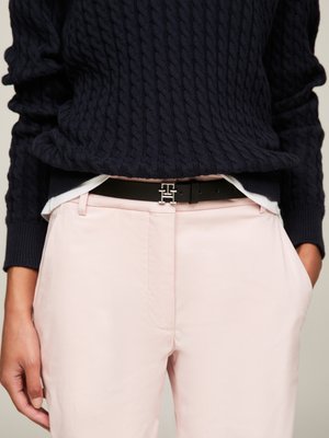 Pull en maille torsadée marine, pantalon rose clair, ceinture noire avec une boucle logo en argent, tissu lisse, style décontracté, silhouette ajustée.