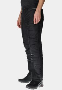 Zwarte geïsoleerde broek met een gewatteerde textuur en elastische tailleband. Beschikt over zijritsen en past goed bij zwarte schoeisel voor gebruik buitenshuis.