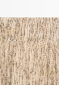 Tessuto a motivi beige con linee verticali di piccoli punti marroni. Texture morbida con un design fluido, adatto per indumenti.
