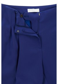 Pantalon bleu marine avec fermeture à crochet et zip, design plissé et tissu lisse et texturé avec une doublure intérieure d'une teinte plus claire.