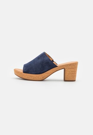 Navy blue suede slide sandals with a cork wedge heel, open toe design, and textured sole. Features a smooth upper and a contrasting heel.